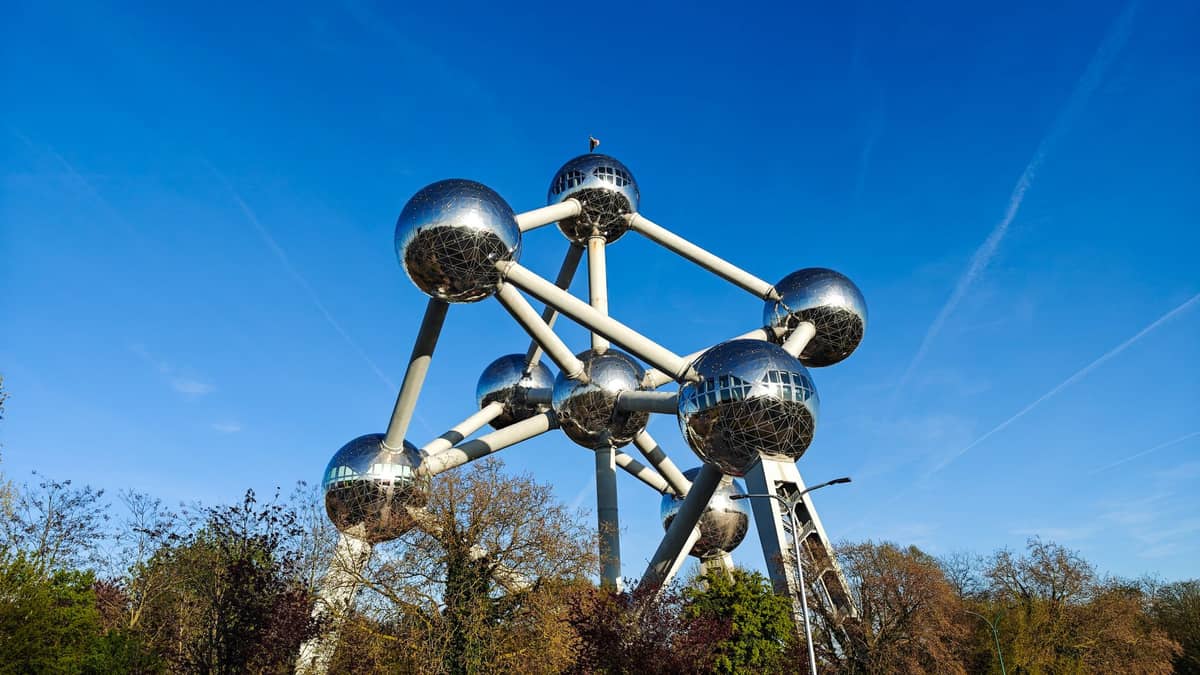 Vista panorâmica do Atomium em Bruxelas sob um céu azul claro com árvores ao redor.