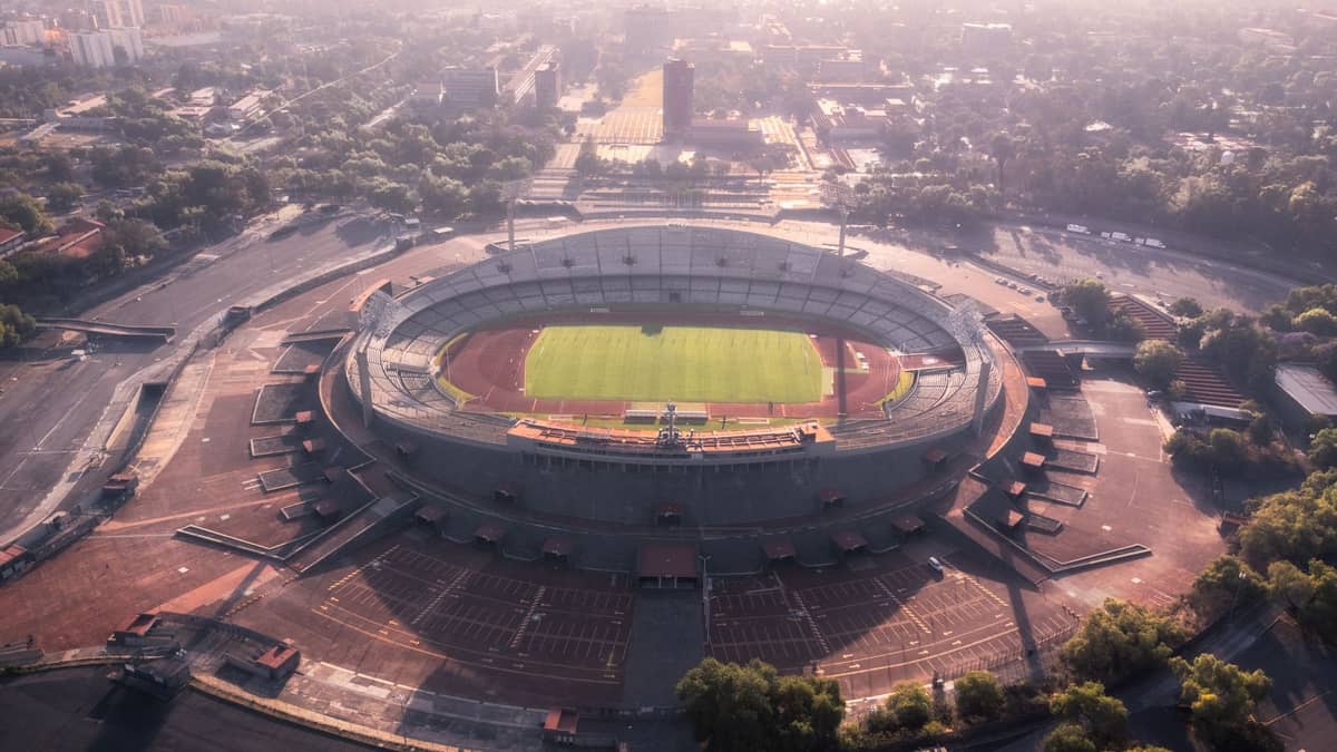 มุมมองทางอากาศของสนามกีฬา Estadio Centenario ในเมืองมอนเตวิเดโอ ประเทศอุรุกวัย ล้อมรอบด้วยต้นไม้และอาคารในเมืองในช่วงกลางวัน