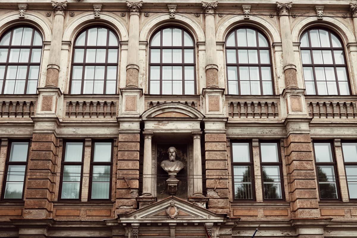Fassade eines prächtigen historischen Gebäudes mit Bogenfenstern und einer markanten Statue in einer Nische, die auf ein bedeutendes Museum in Riga hindeutet.