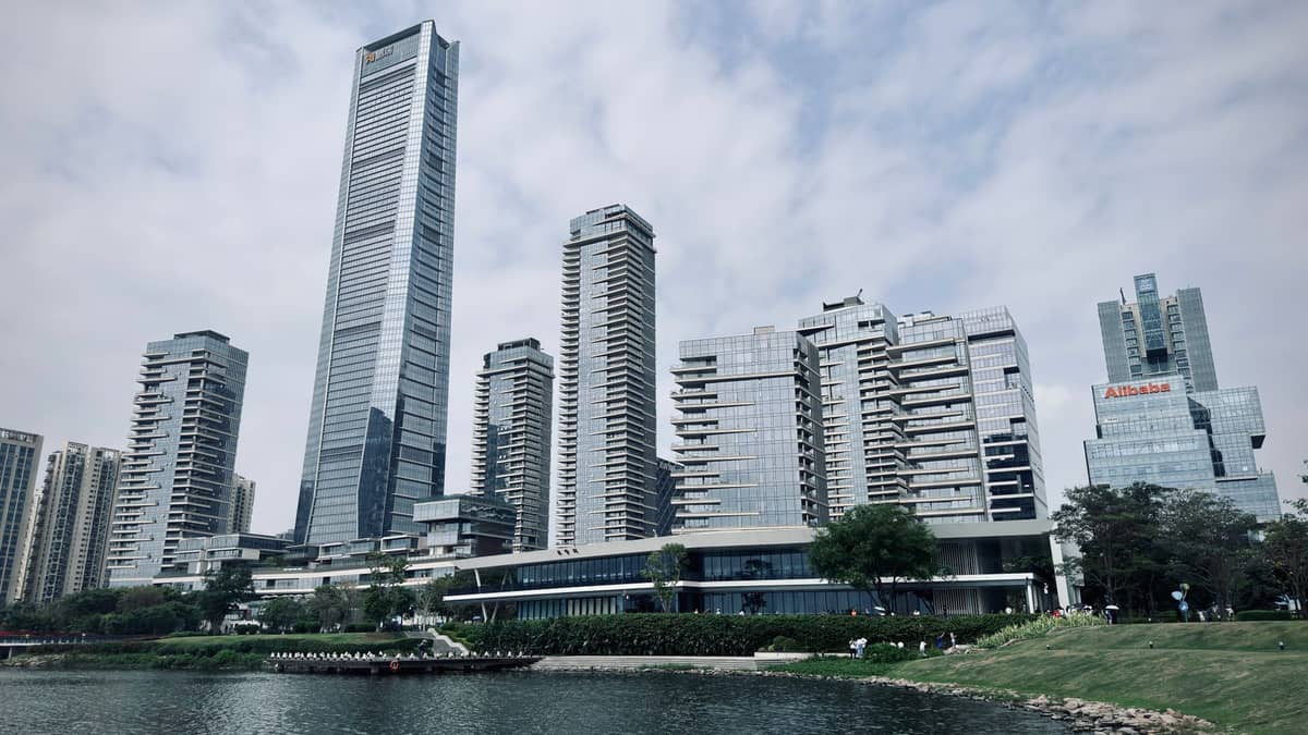 Skyline de Shenzhen com o Ping An Finance Centre e outros arranha-céus modernos erguendo-se acima de um parque à beira-mar em um dia nublado.