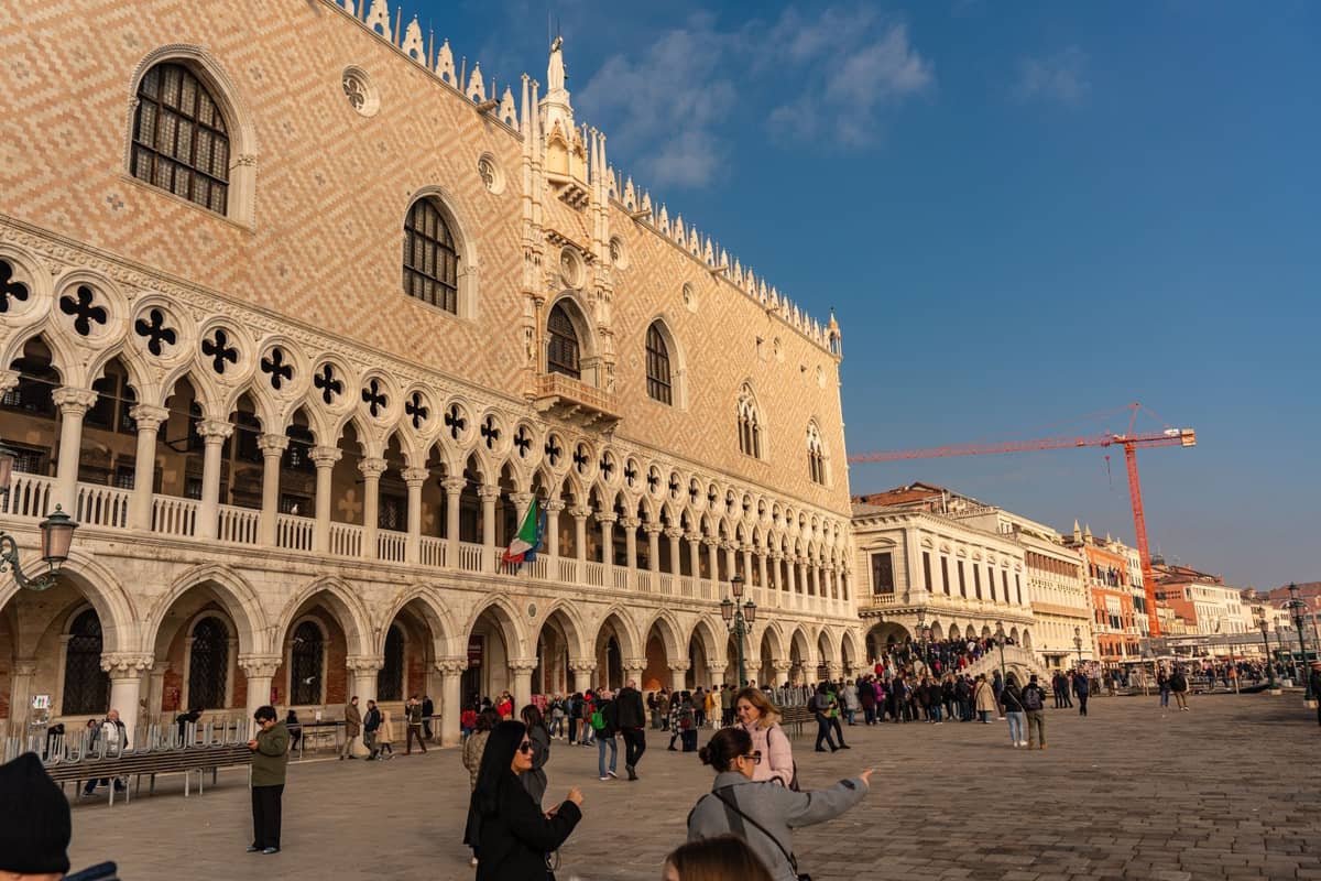 Der Dogenpalast in Venedig mit einer sichtbaren Schlange von Besuchern, die an einem sonnigen Tag draußen warten.