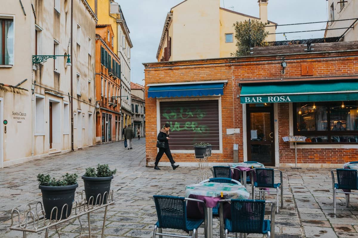 Ein kleiner venezianischer Platz mit Tischen im Freien vor der Bar Rosa, der lokales, touristenfreies Speisen in Venedig heraufbeschwört.