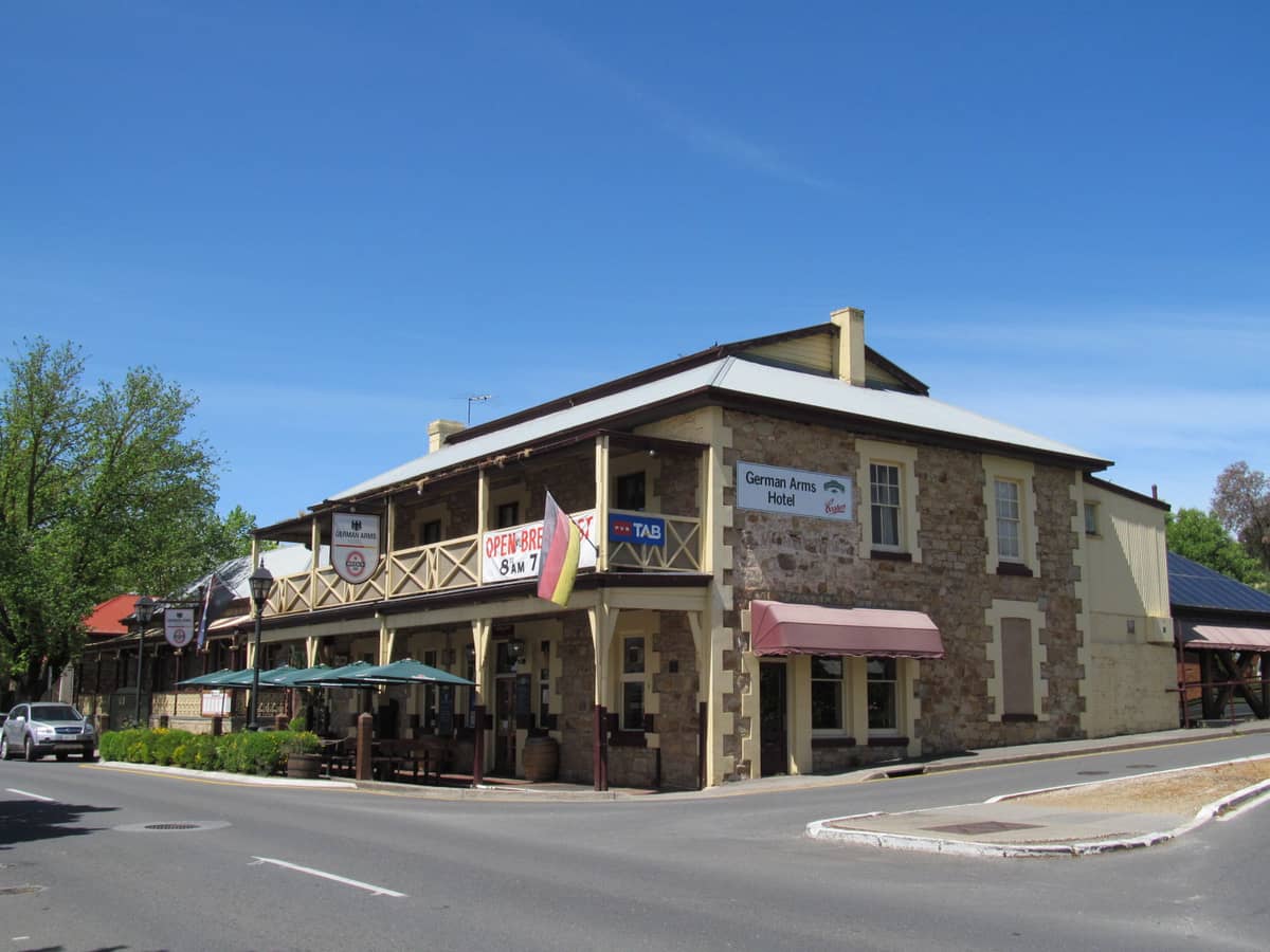 Historisches Gebäude des German Arms Hotel in Hahndorf, Adelaide Hills, mit Steinmauern, Balkonen und Straßenansicht unter einem klaren blauen Himmel
