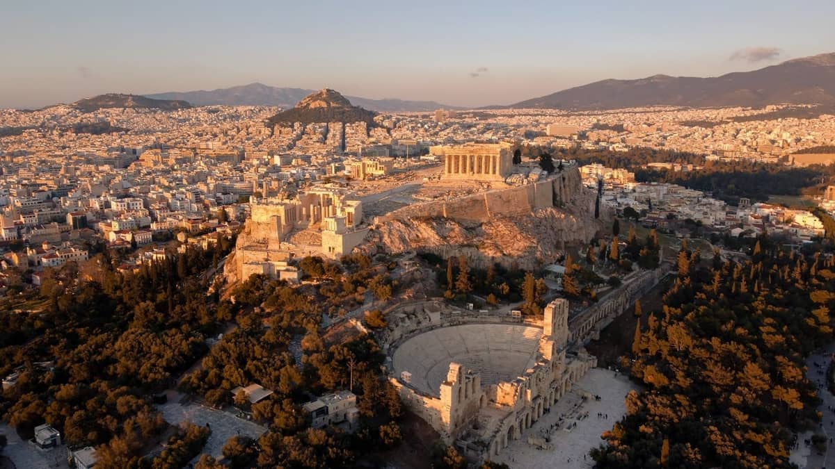Luftaufnahme der Akropolis in Athen mit dem Parthenon und dem Odeon des Herodes Atticus, umgeben von der Stadt und den Bergen.