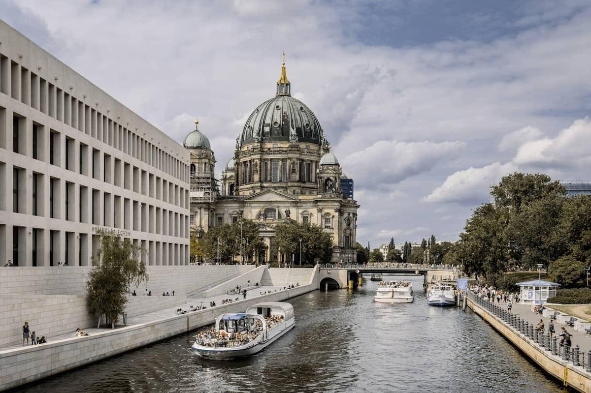 Vista de la Catedral de Berlín en la Isla de los Museos con barcos en el río Spree y edificios modernos a la izquierda.