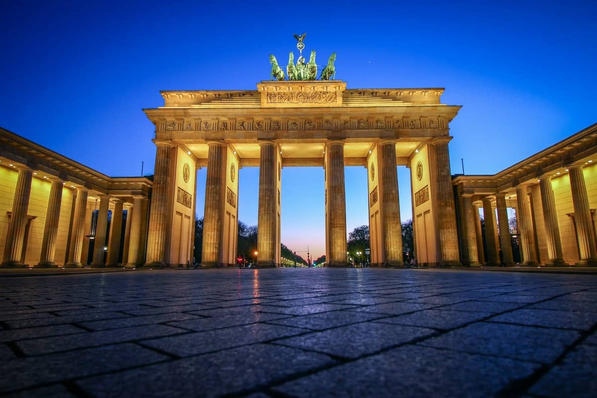 Puerta de Brandeburgo iluminada al amanecer con cielo azul profundo, primer plano despejado y detalles arquitectónicos nítidos.