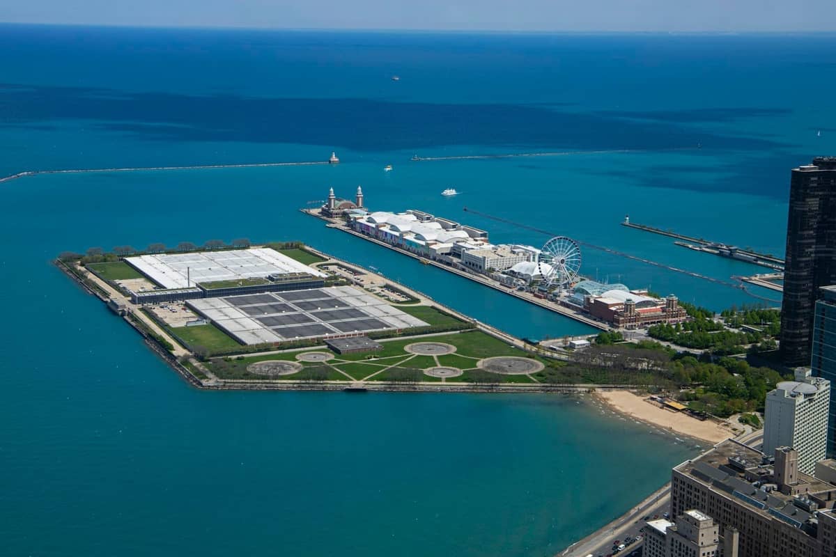 Luftaufnahme des Navy Pier, der sich in den Lake Michigan erstreckt, mit dem Riesenrad, blauem Wasser und der Skyline von Chicago.