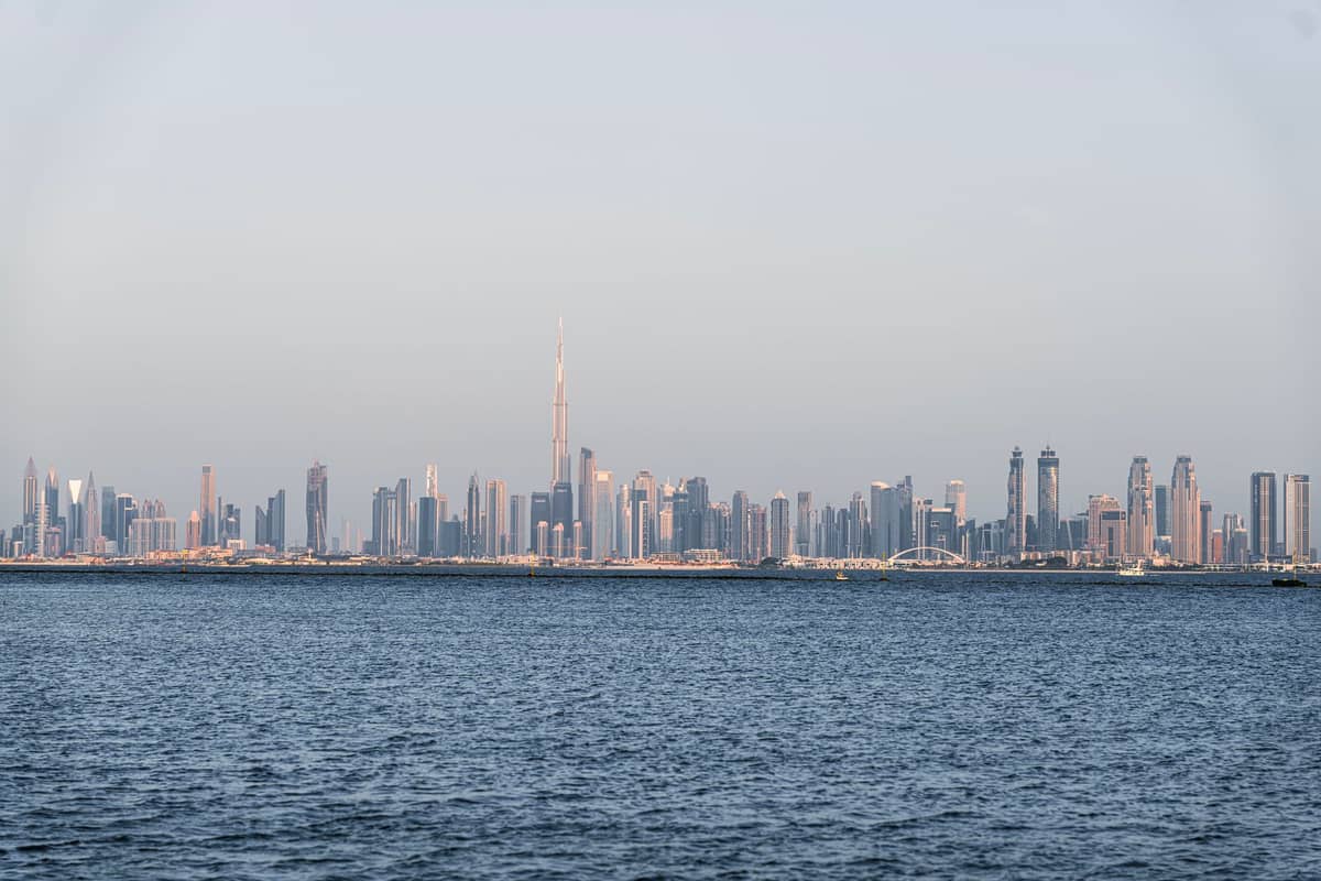 Panoramablick auf Dubais moderne Skyline mit dem Burj Khalifa in der Mitte, vom Wasser aus unter klarem Himmel.