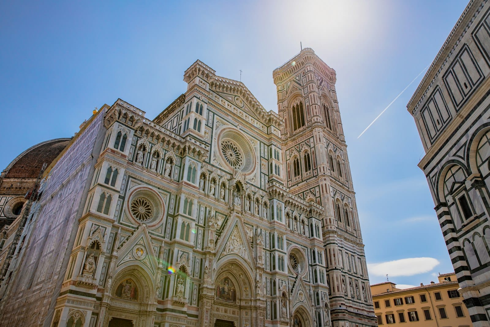 มุมมองไวด์แองเกิลของด้านหน้าและหอระฆังของ Duomo di Firenze ภายใต้ท้องฟ้ายามเที่ยงวันที่สดใส
