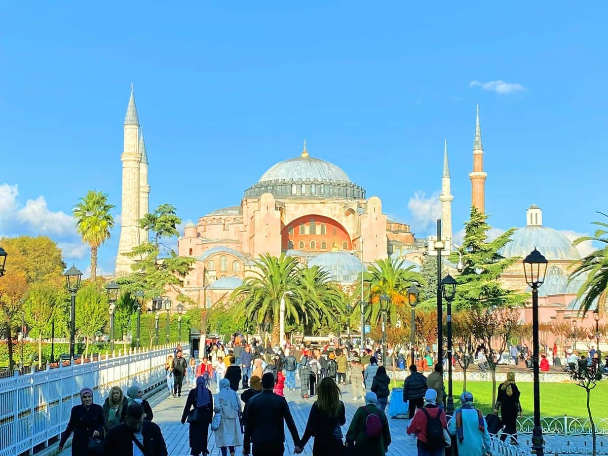 Słoneczny widok na Hagia Sophia z tłumami ludzi spacerujących ścieżką na historycznym półwyspie Stambułu.