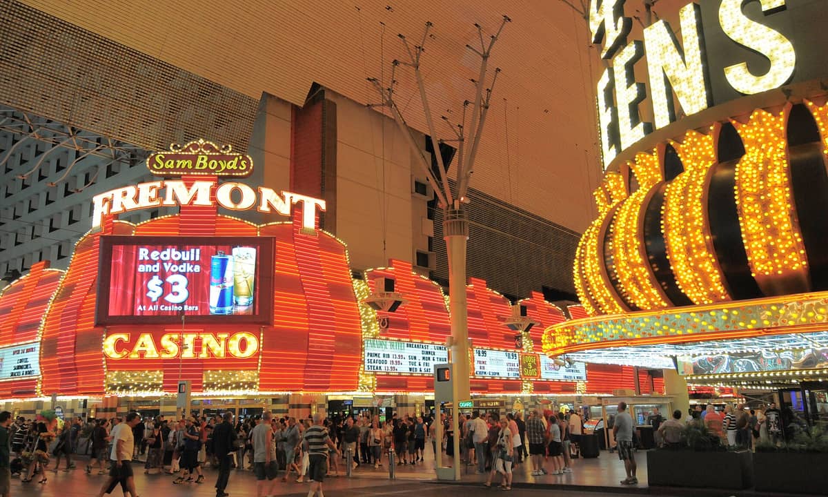 ฝูงชนรวมตัวกันในยามค่ำคืนใต้แสงไฟนีออนสว่างไสวของ Fremont Casino และ Four Queens ในใจกลางเมือง Las Vegas ซึ่งสว่างไสวด้วยหลังคา LED ด้านบน