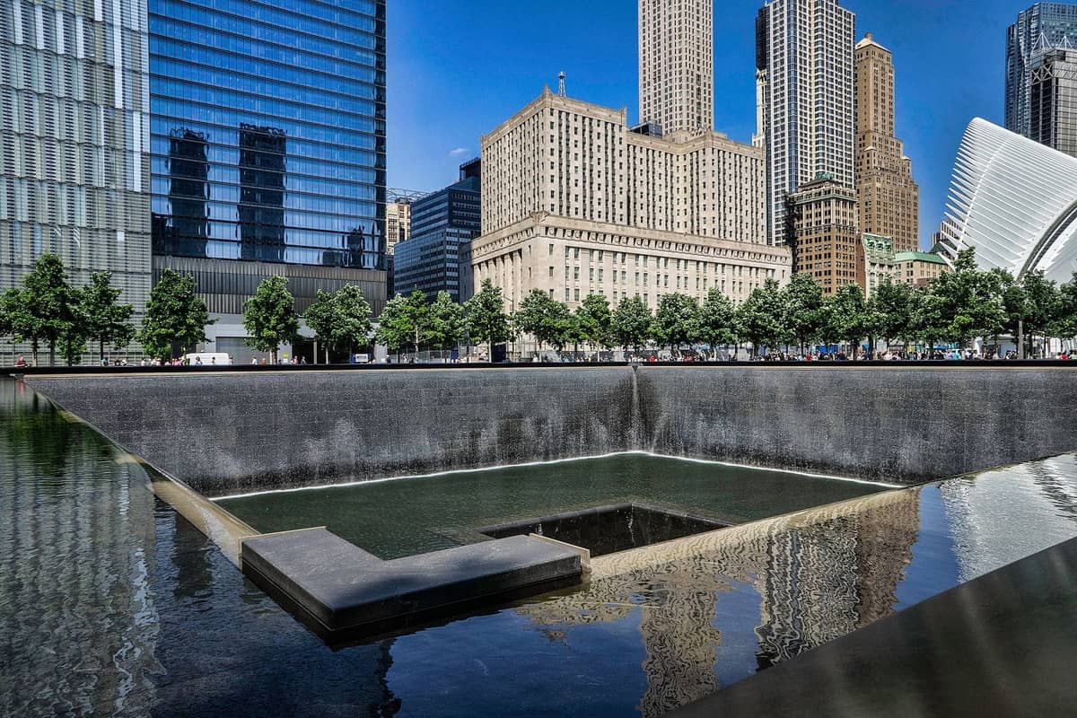 สระสะท้อนน้ำของ 9/11 Memorial ใน Lower Manhattan พร้อมตึกระฟ้าและ Oculus เป็นฉากหลังในวันที่ท้องฟ้าแจ่มใส