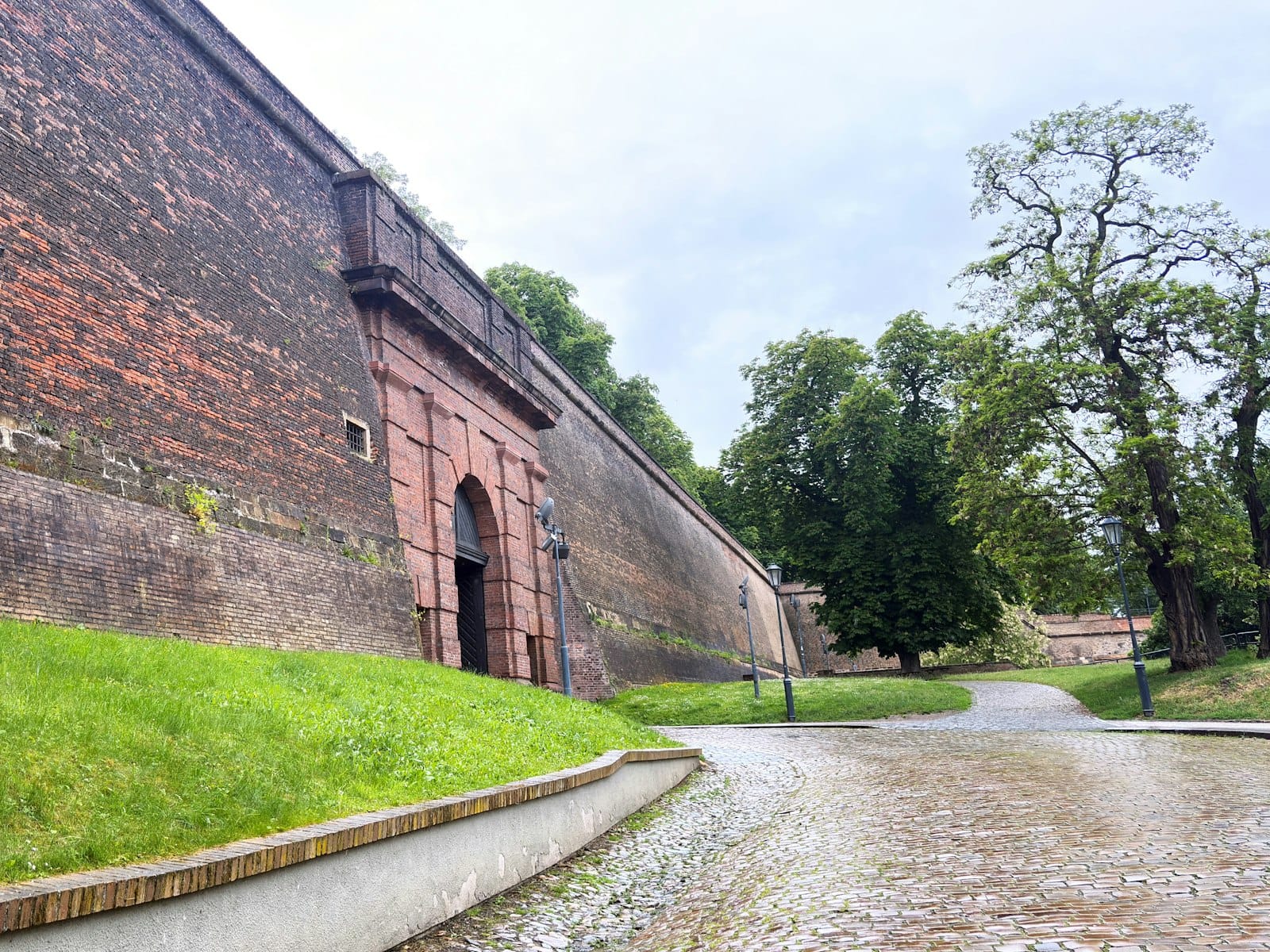 Malawak na bato na pader ng kuta na may arko na gate, daan na bato, at mga puno malapit sa Vyšehrad sa Prague