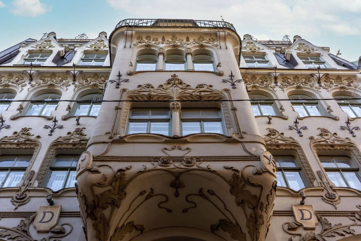 Nahaufnahme der verzierten Jugendstilfassade eines Gebäudes in Riga mit aufwendigen Stuckblumenmustern und skulptierten Details über den Fenstern.