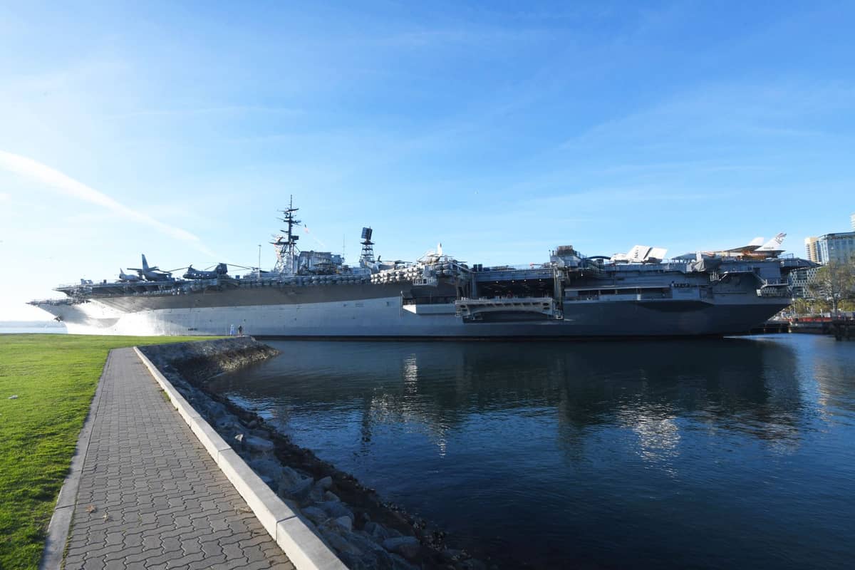 เรือบรรทุกเครื่องบินพิพิธภัณฑ์ USS Midway จอดเทียบท่าอยู่ริมทางเดินชายฝั่งของ San Diego ในวันที่อากาศแจ่มใสท้องฟ้าสีฟ้า