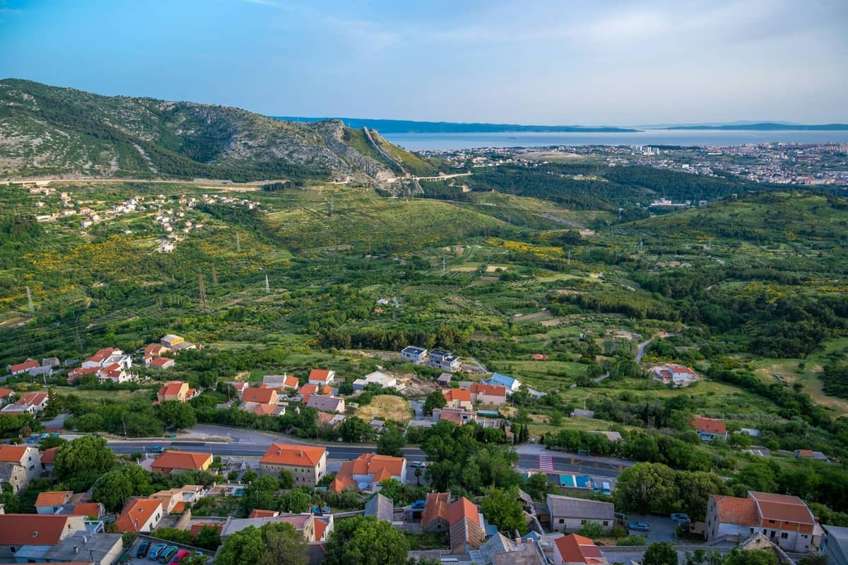 Panoramablick auf ein grünes Tal mit vereinzelten Häusern und Bergen, das wahrscheinlich die Gegend rund um Split und mögliche Ausflugsziele zeigt.