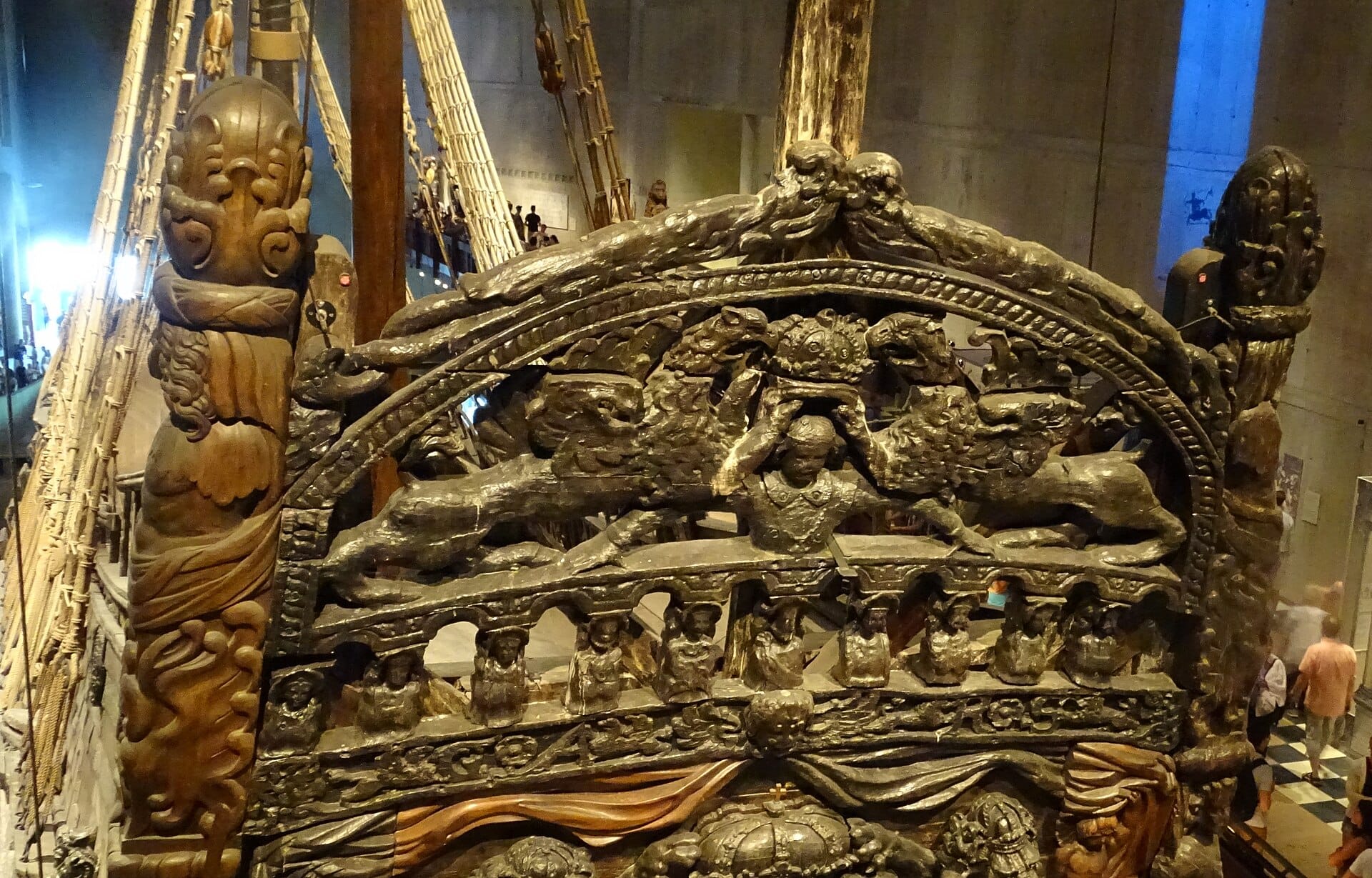ภาพระยะใกล้ของท้ายเรือรบ Vasa ที่ประดับประดาอย่างวิจิตรภายใน Vasa Museum ในสตอกโฮล์ม พร้อมนักท่องเที่ยวอยู่เบื้องหลัง