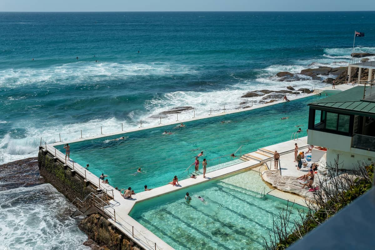 Bondi Icebergs Meeresbecken mit Blick auf brechende Wellen, mit Menschen die an einem sonnigen Tag schwimmen und entspannen.