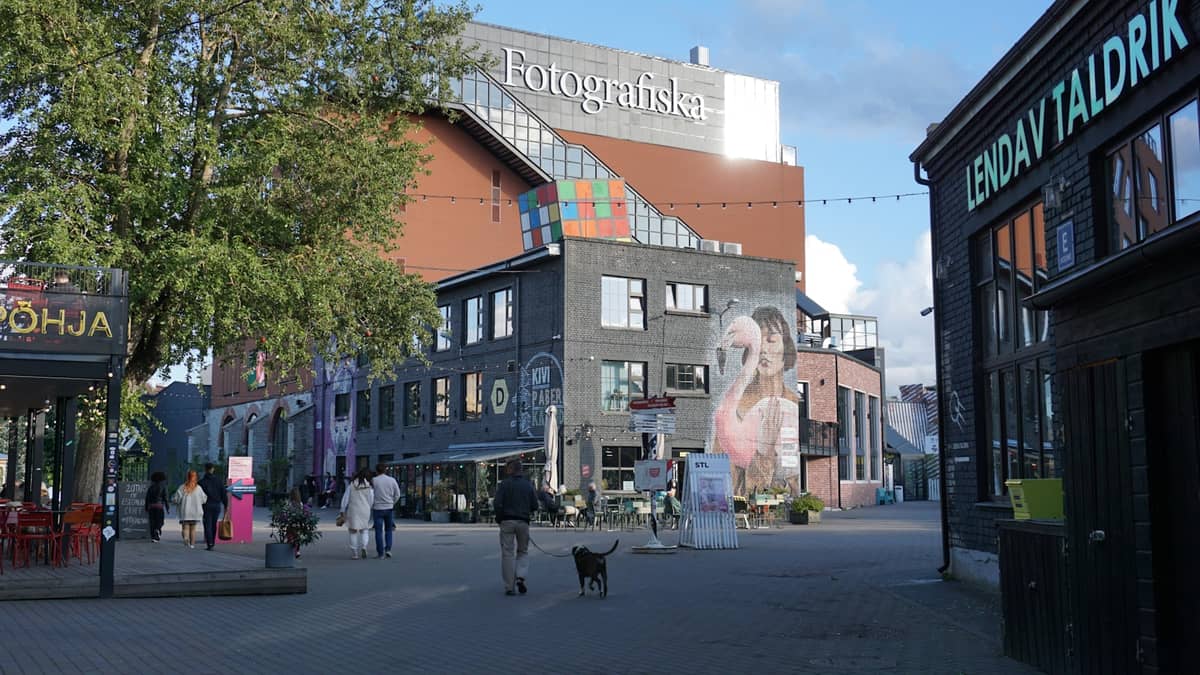 Personas caminando frente al edificio de Fotografiska en Telliskivi Creative City, el barrio creativo de Tallinn con arte urbano y ambiente moderno.