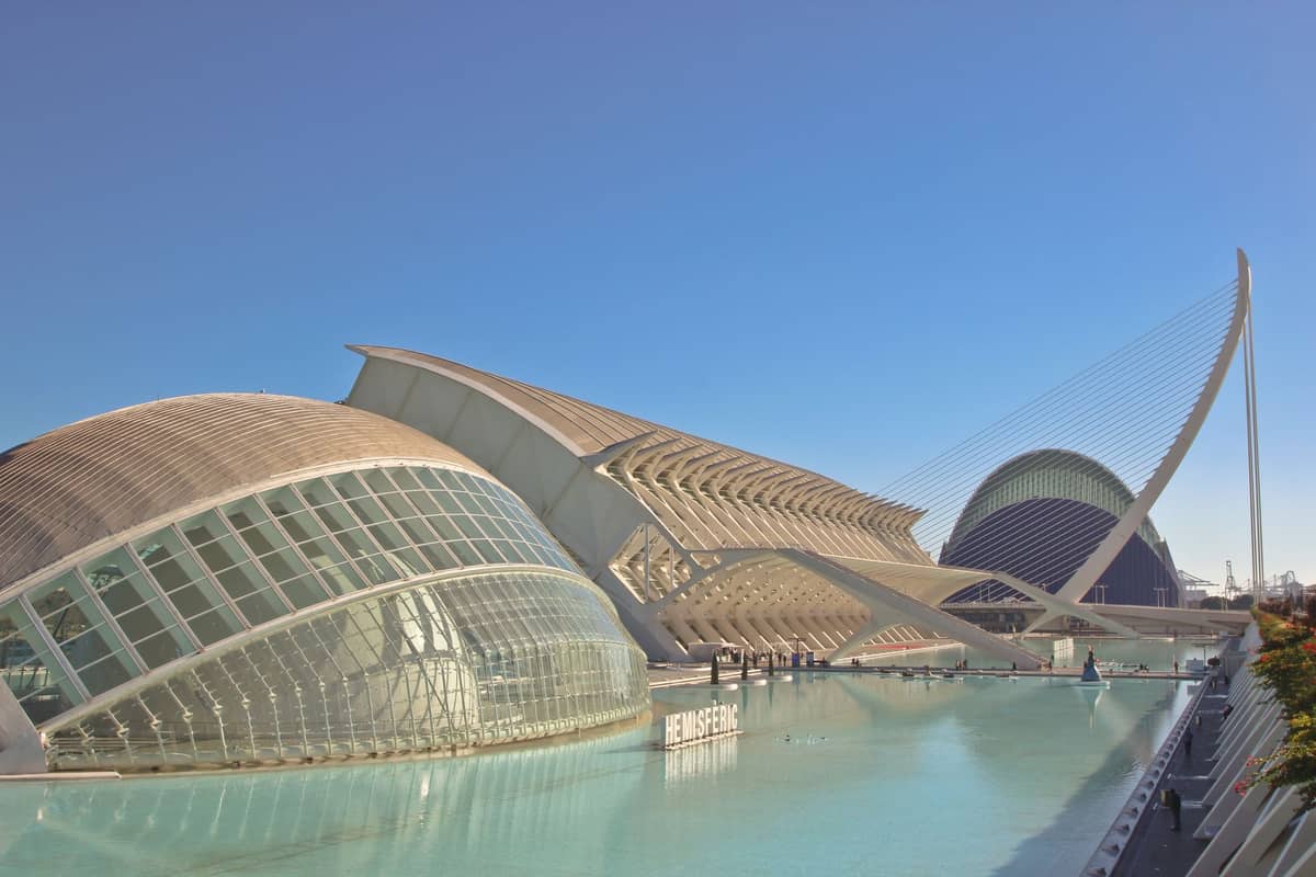 Weitwinkelansicht der Ciudad de las Artes y las Ciencias in Valencia mit moderner Architektur, blauen Wasserbecken und einem hellen, klaren Himmel.