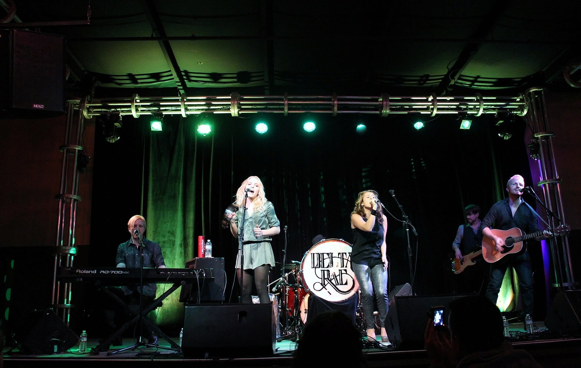 Banda en vivo actuando bajo luces verdes en 3rd & Lindsley, Nashville, con teclado, batería, guitarra y dos vocalistas en el escenario.