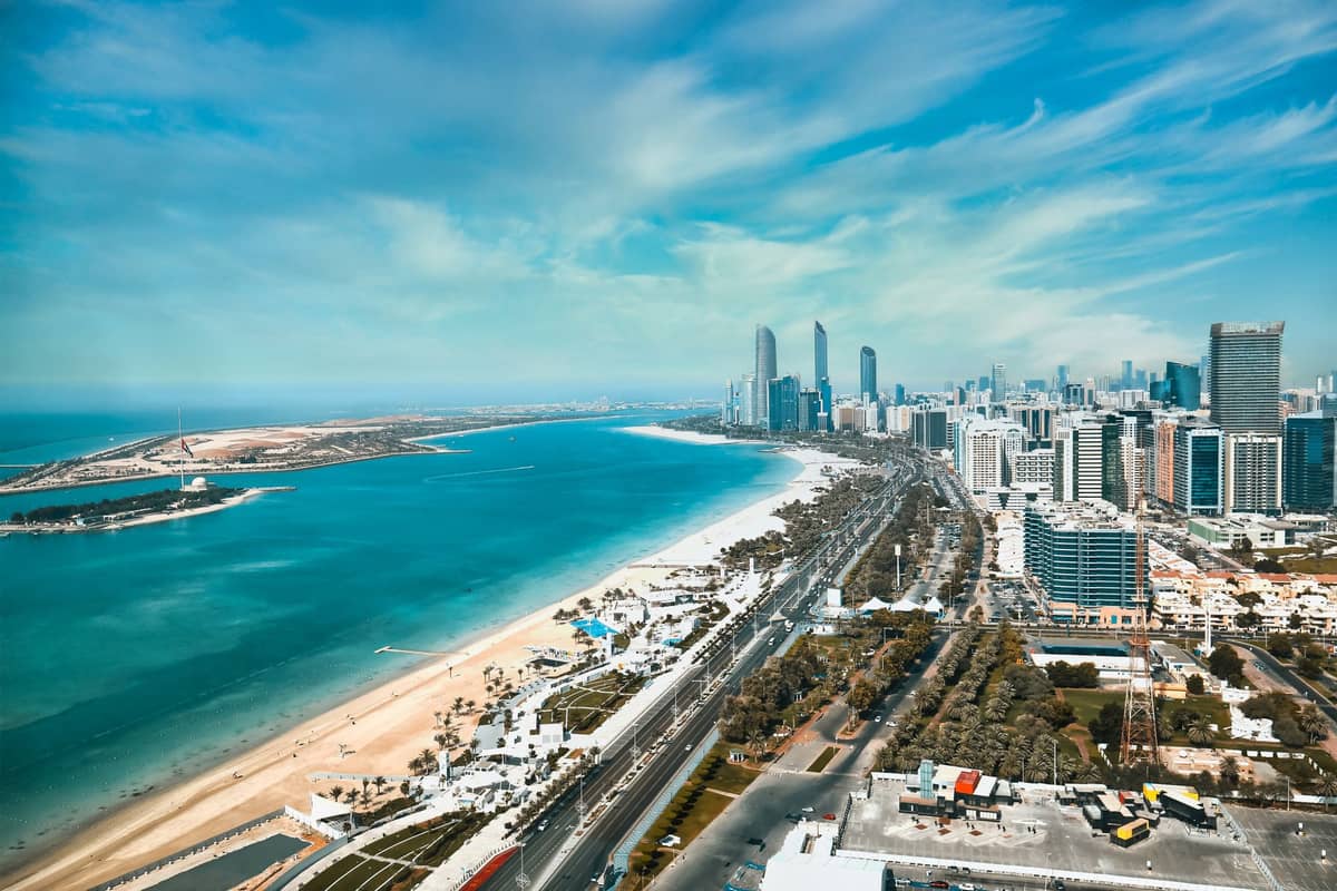 Weites Panorama der Abu Dhabi Corniche mit Skyline und blauem Golfwasser — Hochhäuser und Uferstraßen unter strahlend hellem Himmel.