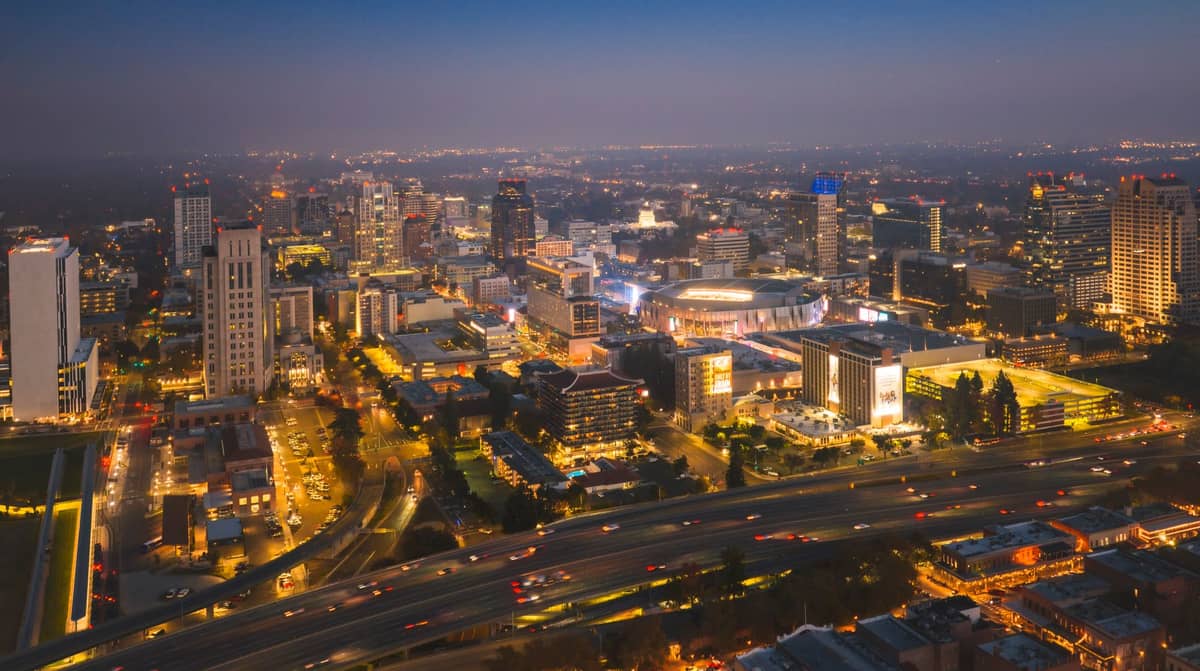 Vista aerea serale dello skyline della città di Adelaide con edifici luminosi e autostrade in primo piano.