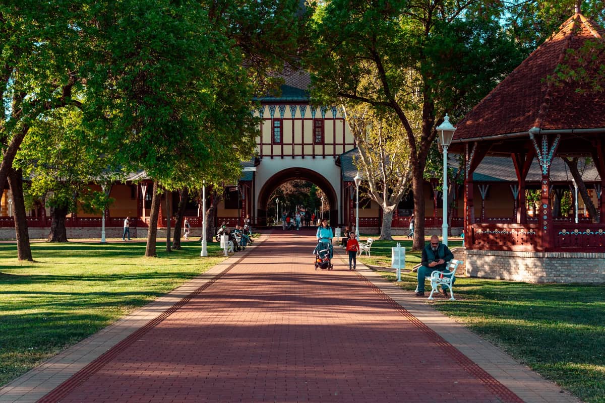 Rodziny z wózkami i dziećmi spacerujące alejkami Elder Park przy historycznym pawilonie w centrum Adelaide, w Australii Południowej.