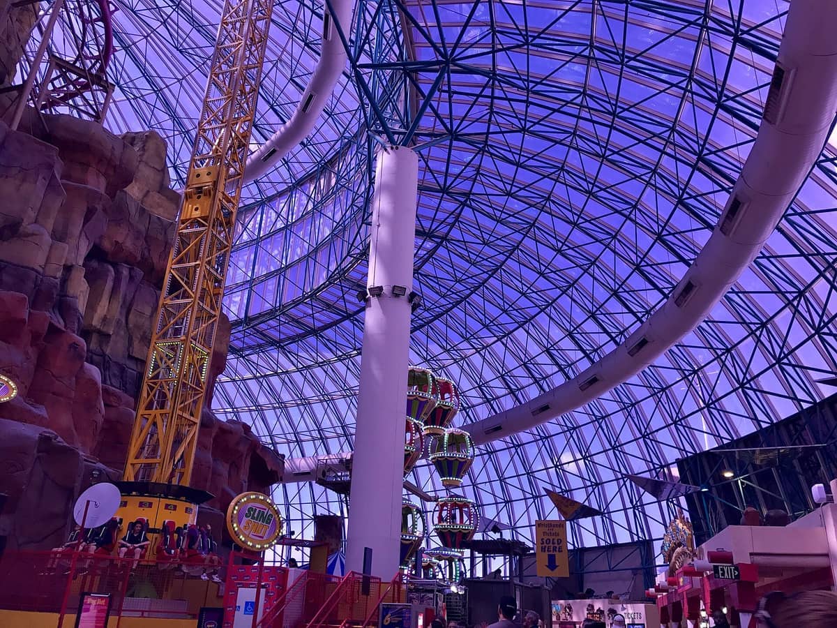 Interior view of Adventuredome at Circus Circus, featuring a yellow thrill ride, artificial rock walls, and the park’s iconic glass dome ceiling.