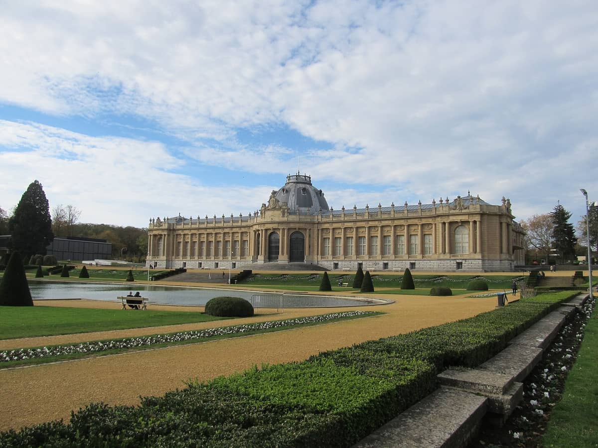 A imponente fachada neoclássica do AfricaMuseum de Tervuren e seus jardins bem cuidados sob um céu parcialmente nublado perto de Bruxelas.
