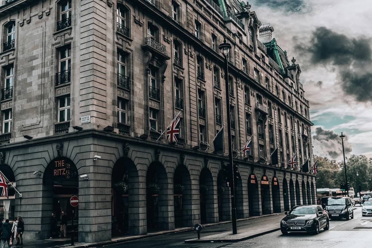 Vista da rua do exterior do hotel The Ritz London com bandeiras britânicas e arquitetura clássica em um dia nublado