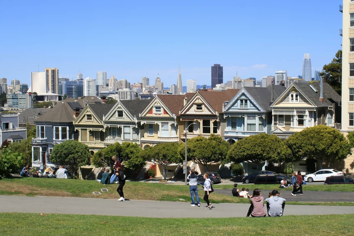 Coloridas casas victorianas conocidas como las Painted Ladies de Alamo Square Park, con el horizonte del centro de San Francisco visible bajo un cielo azul despejado.