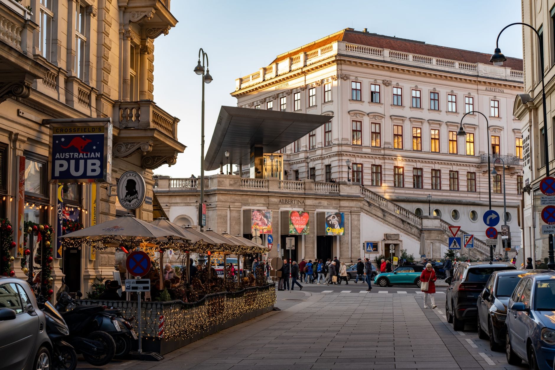 Das Albertina Museum in Wien zur goldenen Stunde: die prächtige Habsburger Palastfassade, die Straßenansicht und das markante moderne Eingangsschutzdach.