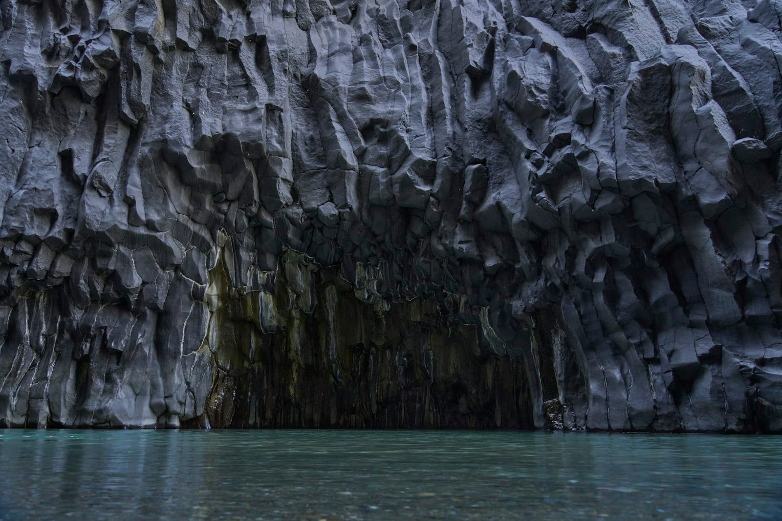 Dramatische Basaltwände steigen senkrecht aus klarem Wasser in der Alcantara-Schlucht auf und zeigen beeindruckende hexagonale Säulen, die von uralten Lavaströmen geformt wurden.