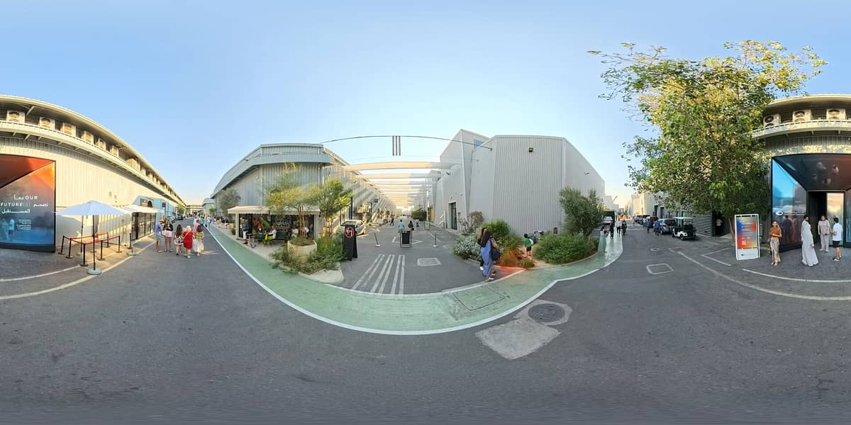 Weitwinkelpanorama der Alserkal Avenue mit modernen, zu Kunstgalerien umgebauten Lagerhallen, Besuchern, Grünflächen und Beschilderung in Dubais zeitgenössischem Kunstbezirk.