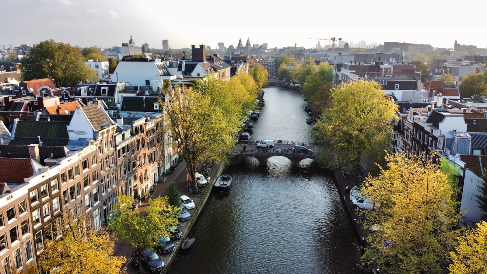 Vista aérea del Canal Ring de Ámsterdam con edificios históricos y puentes bordeando la vía fluvial curva, mostrando el icónico trazado urbano de la ciudad.