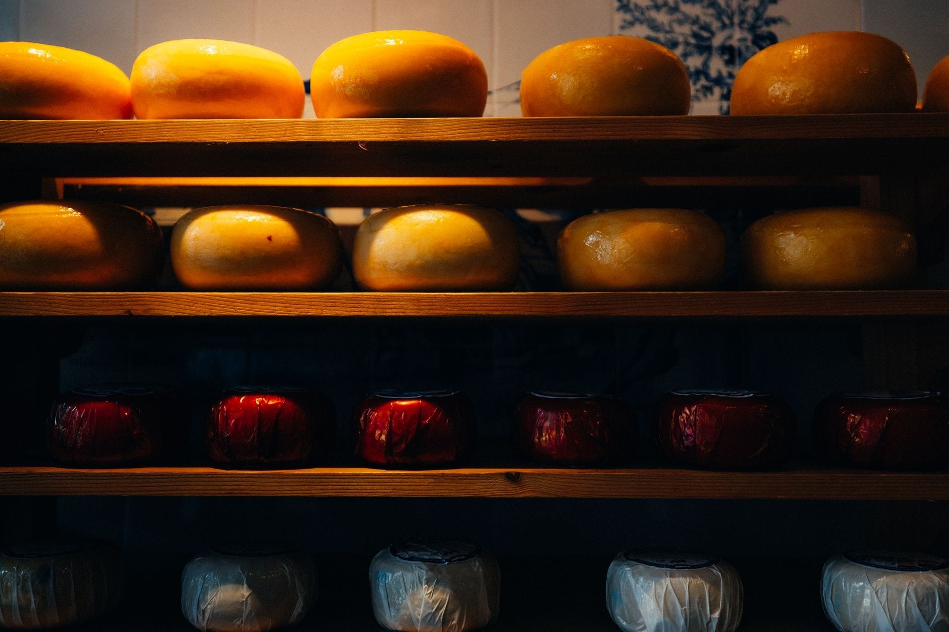 Estantes repletos de ruedas de queso holandés en una exposición con iluminación cálida, que refleja la tradicional cultura quesera de Ámsterdam.