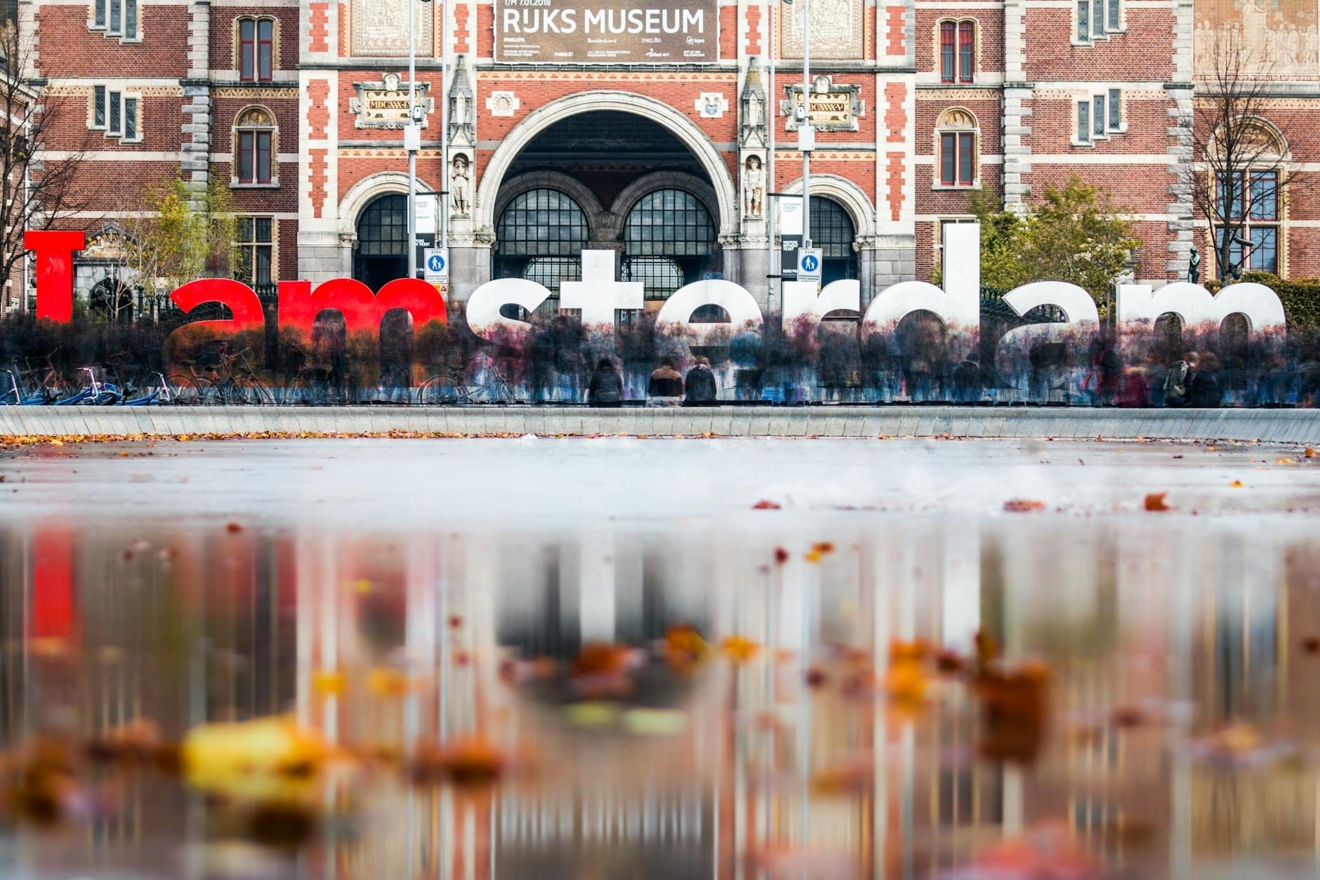 Vista del Rijksmuseum con el famoso letrero 'I amsterdam' y hojas de otoño flotando en el estanque reflectante de enfrente.