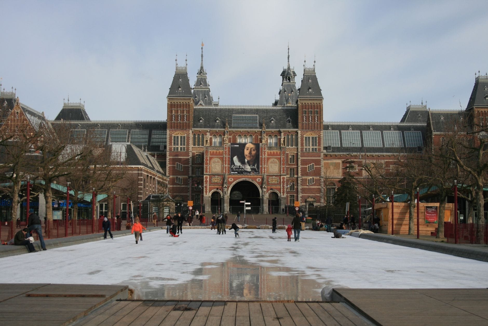 Personas patinando en la pista de hielo de Museumplein frente al Rijksmuseum en Ámsterdam durante el invierno.