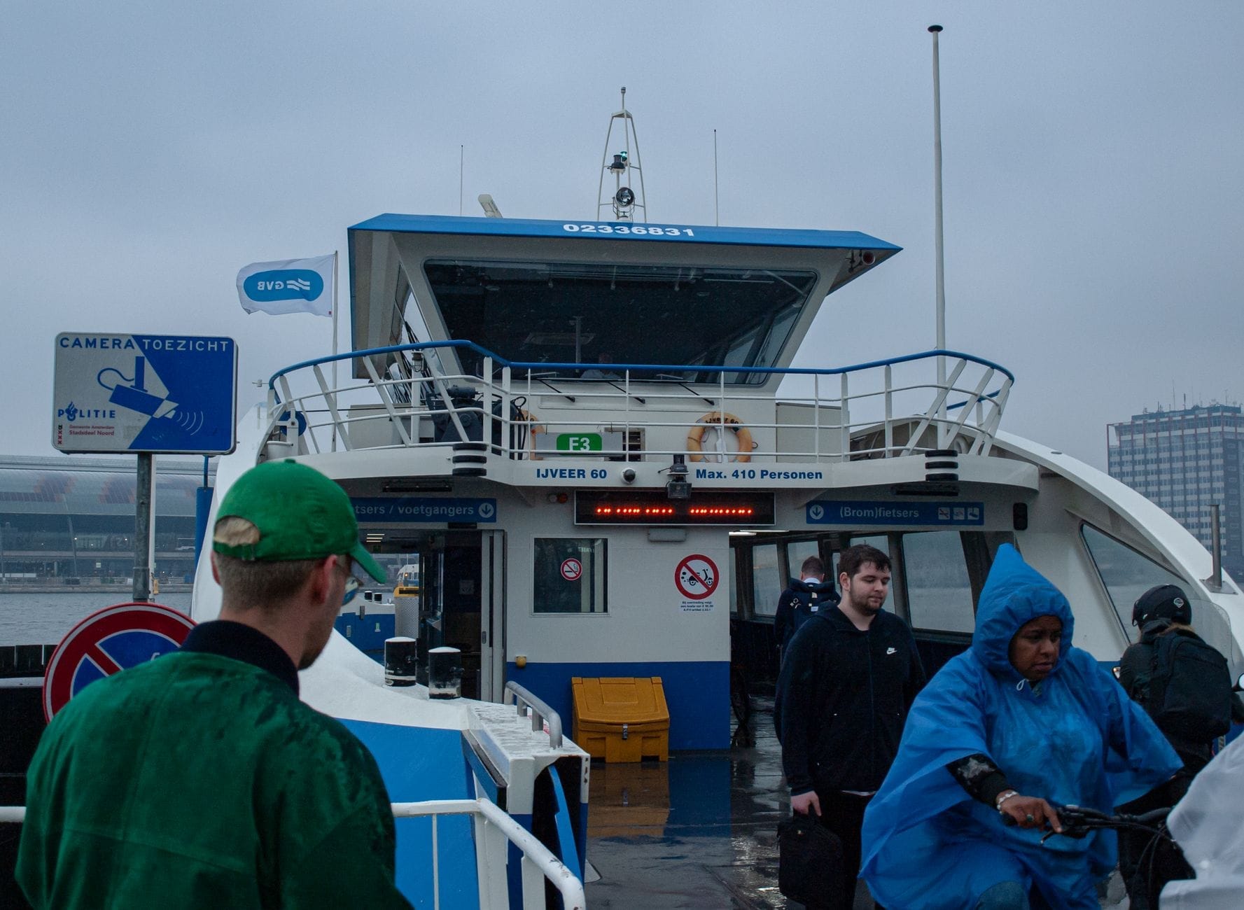 Mọi người rời khỏi phà GVB tại Amsterdam-Noord vào một ngày nhiều mây, với bến phà hiện ra rõ ràng.