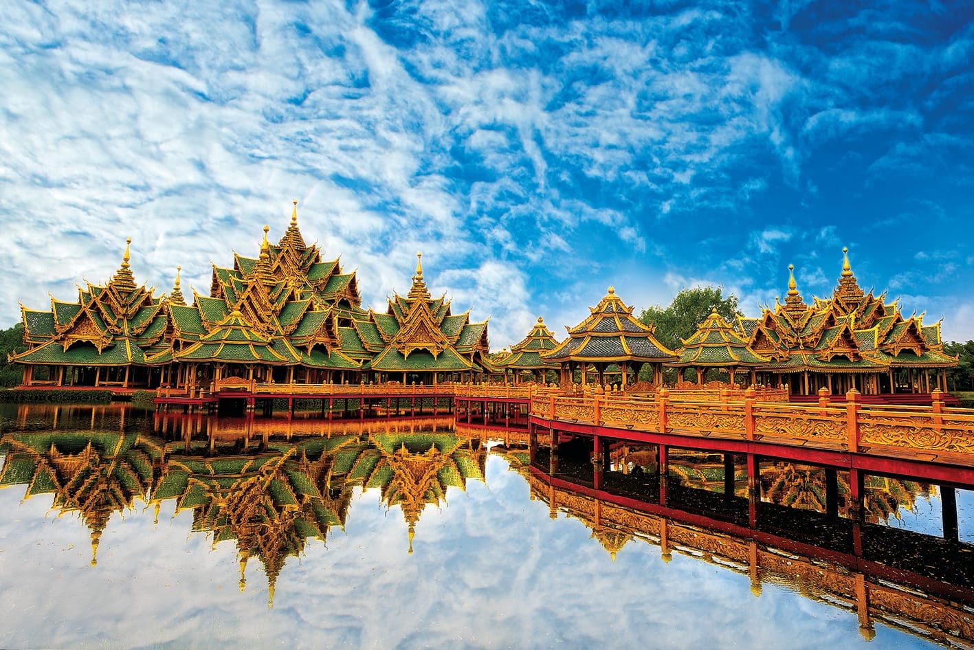 Padiglioni tradizionali thailandesi all'Ancient City Muang Boran di Bangkok con tetti decorati riflessi nell'acqua sotto un cielo drammatico