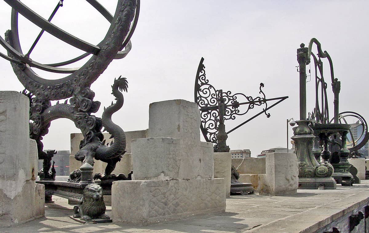 Bronzene Qing-zeitliche Astronomieinstumente mit Drachenmotiven auf der Dachterrasse der Alten Sternwarte Peking, mit Blick auf die Skyline der Stadt.