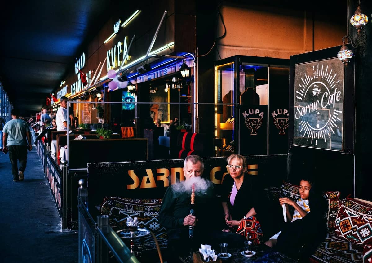 People enjoying shisha at an atmospheric outdoor bar with neon lights and Turkish rugs, capturing authentic nightlife in Antalya.
