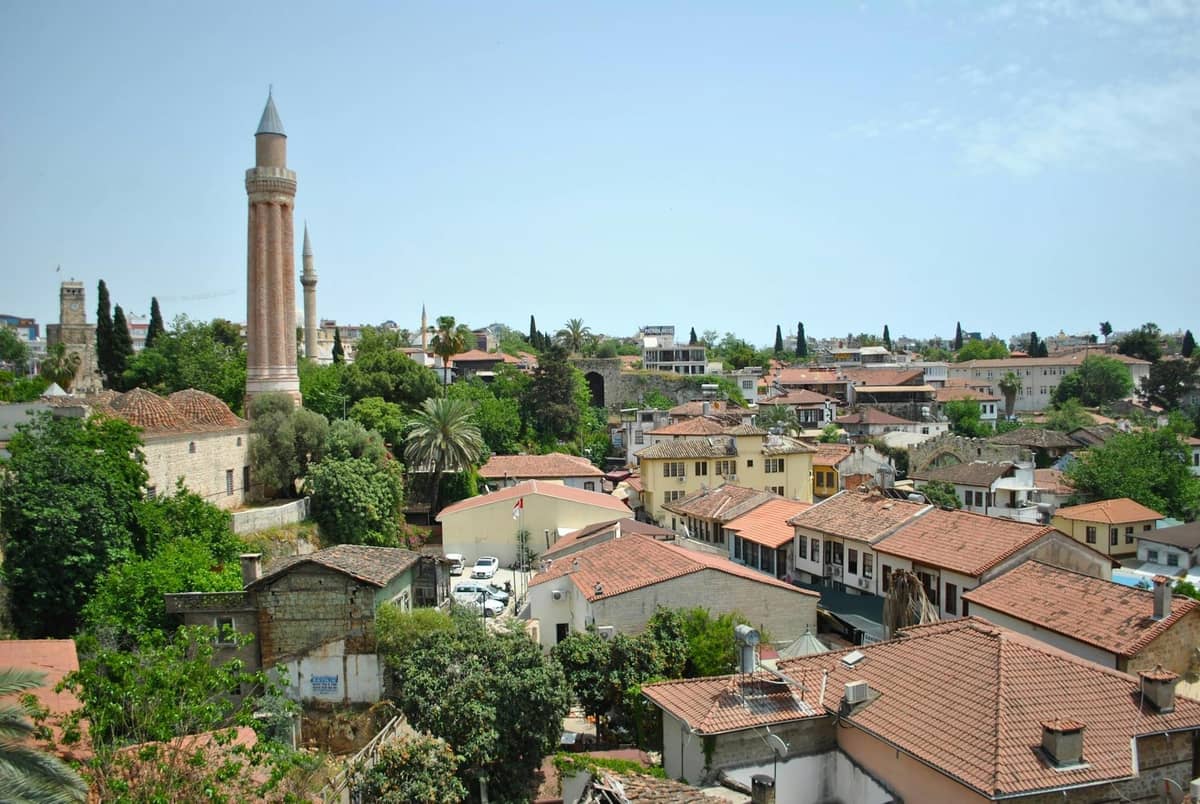Panoramic view of Kaleiçi with Ottoman houses, historic Yivli Minaret, and orange-tiled rooftops surrounded by greenery in Antalya’s Old Town.