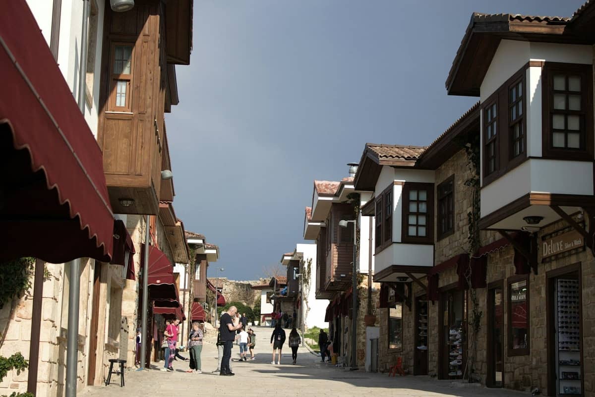 Street scene in Kaleiçi Old Town with Ottoman-style buildings, stone pavement, and tourists walking under daylight