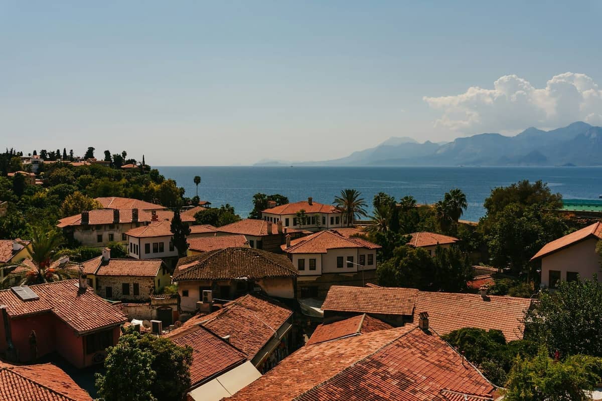 Panoramic view over Antalya old town rooftops with the sea and mountains in the background on a sunny day.