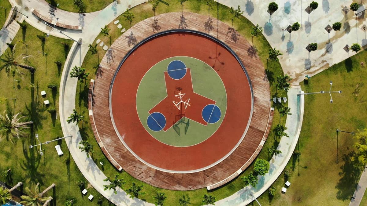 Aerial view of a landscaped city park in Antalya featuring a large, modern circular playground or sports area surrounded by green lawns and walkways.