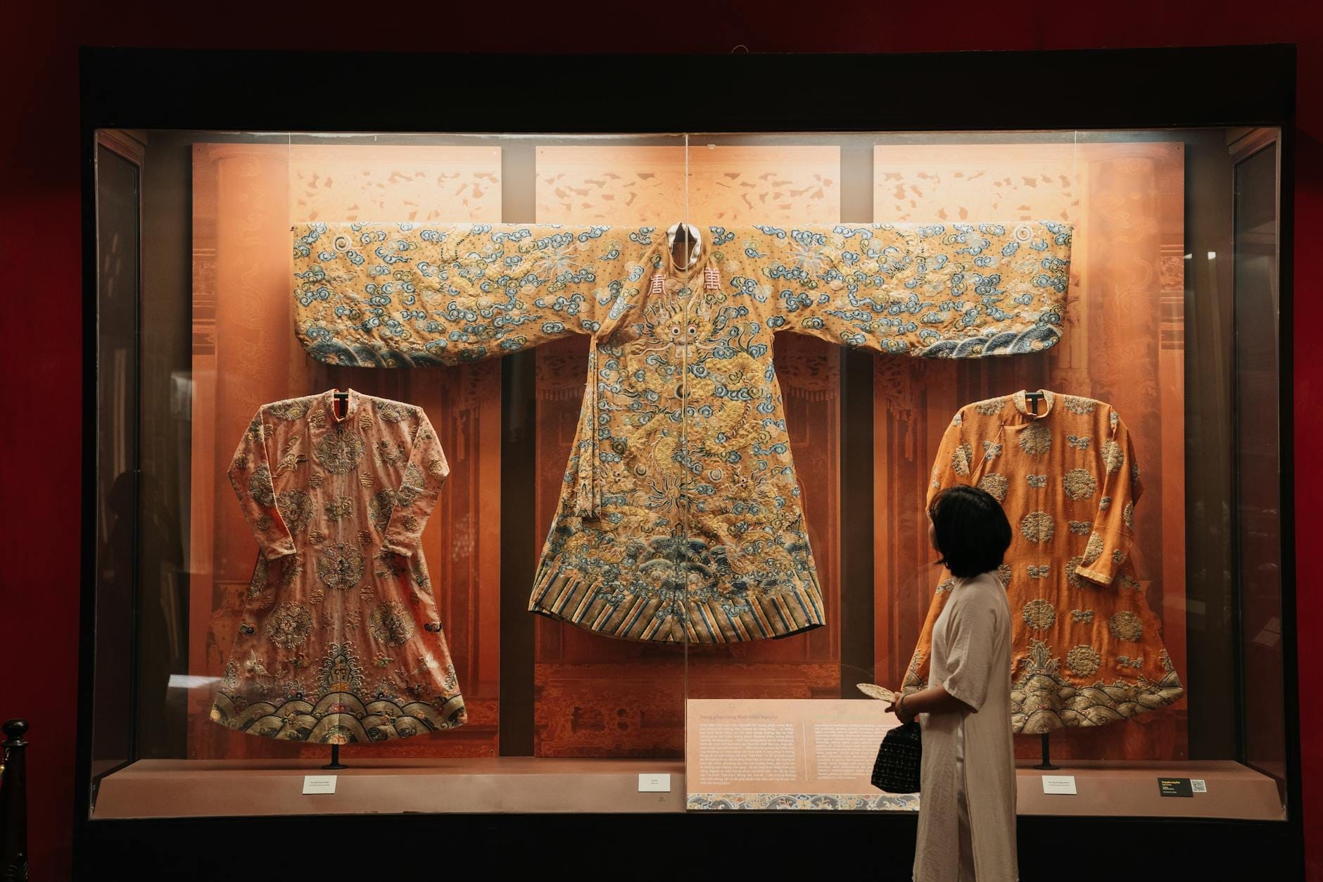 Un visitante observa prendas tradicionales de áo dài con bordados ornamentados expuestas en una vitrina en el Áo Dài Museum de Ho Chi Minh City.