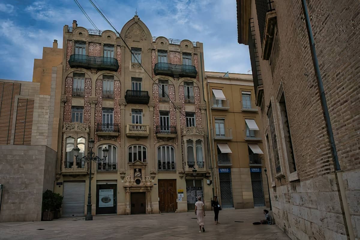 Facciata di Casa San Vicente in stile Modernista su una piazza di Valencia, con ricchi dettagli Art Nouveau e balconi decorativi sotto un cielo parzialmente nuvoloso.