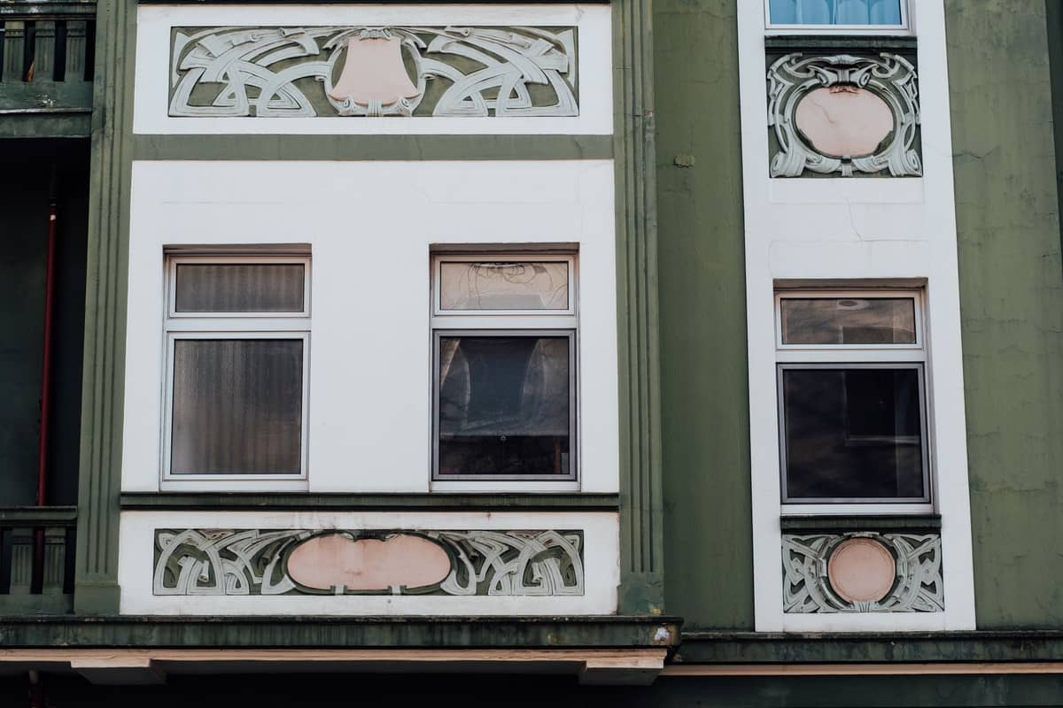 Close-up da fachada de um edifício com motivos florais Art Nouveau em verde e branco e designs geométricos ao redor das janelas
